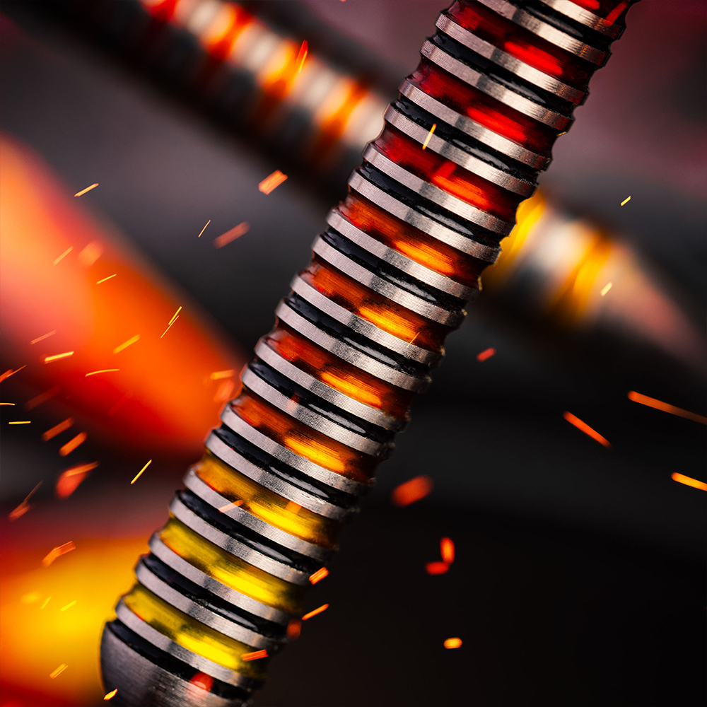A close-up of a steel dart with a grooved, metallic shaft that glows in bright shades of red, orange and yellow. Dark rings separate the bright sections, which are reminiscent of molten metal. Sparks fly around the hot Furnace barrel.