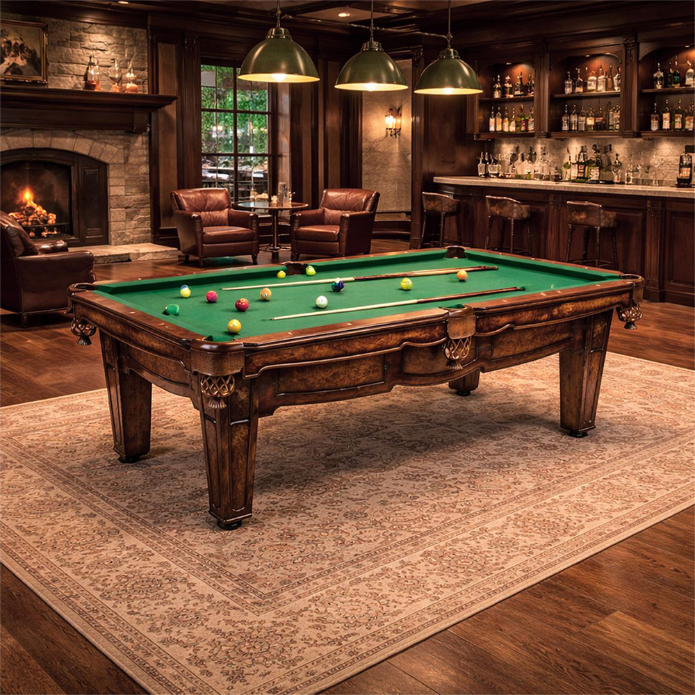 Salle de billard premium avec grande table sculptée recouverte de feutre vert. À gauche, feu dans la cheminée en pierre et fauteuils en cuir. À droite, bar en bois bien garni avec bouteilles et tabourets.