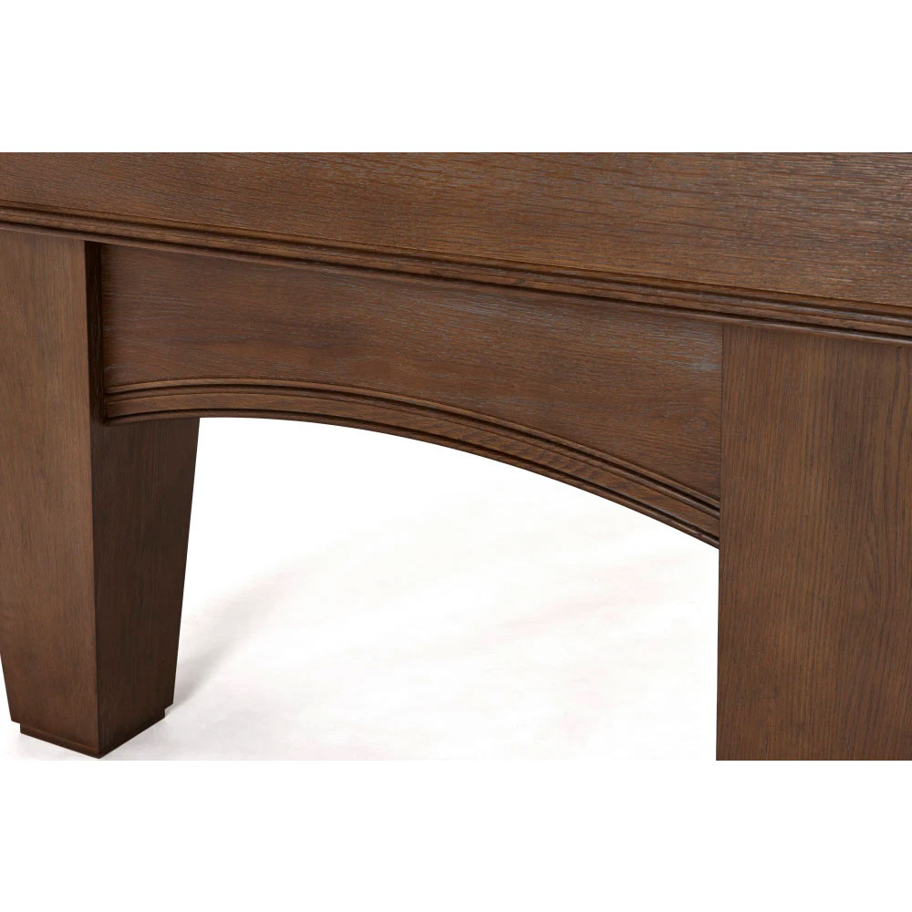 Close-up of the side of an Brunswick Winfield pool table in a nutmeg finish. The sturdy wooden construction features a curved arch shape between the table legs with a distinct wood grain and fine decorative mouldings along the top edge of the frame.