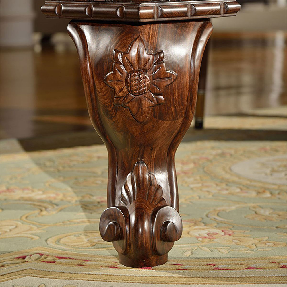 Gros plan sur le pied somptueusement tourné de la table de billard Arizona, en bois massif foncé. Sculpture élaborée représentant une fleur stylisée et des ornements en forme de vrilles au niveau du pied, veinage du bois apparent, sur un tapis vert clair.
