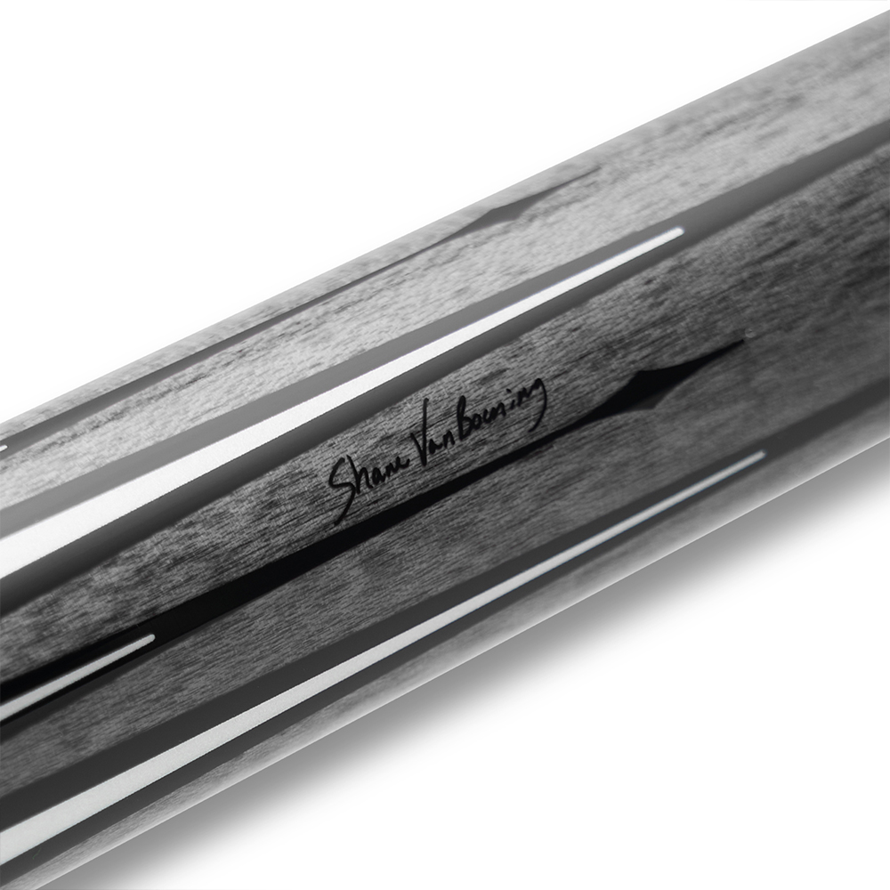 Gros plan en noir et blanc d'une queue de billard présentant un grain de bois visible et plusieurs fines rayures claires. Au centre, la signature « Shane Van Boening » en italique est clairement reconnaissable.