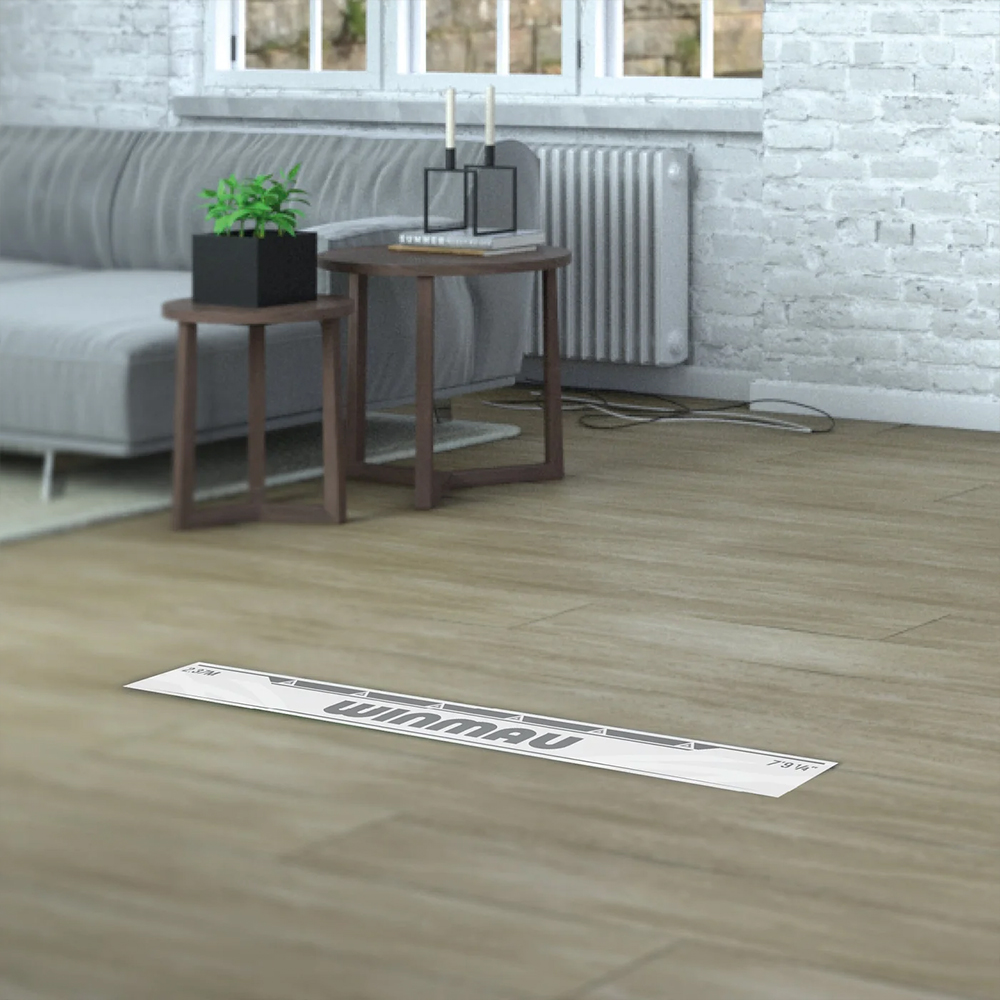 White, self-adhesive ‘ Winmau ’ throw line on a light brown wooden floor. In the centre is the grey ‘ Winmau ’ logo, flanked by precise markings for foot placement when playing darts. It helps you maintain the exact distance.