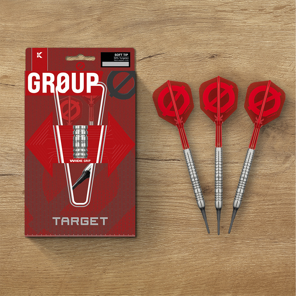 Trois fléchettes souples Target série GROUP sont posées sur une table en bois, près d’un emballage rouge. Elles ont des corps argentés striés en tungstène 50 %, des tiges rouges, des ailettes K-Flex GROUP et des pointes Cryo noires.