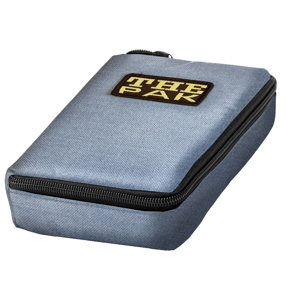 Rectangular darts case "The Pak" in a light blue denim look, upright. Durable polyester fabric with a denim texture. Black zip at the top. Brown logo patch with gold-coloured "THE PAK" lettering. Protection for darts and accessories.