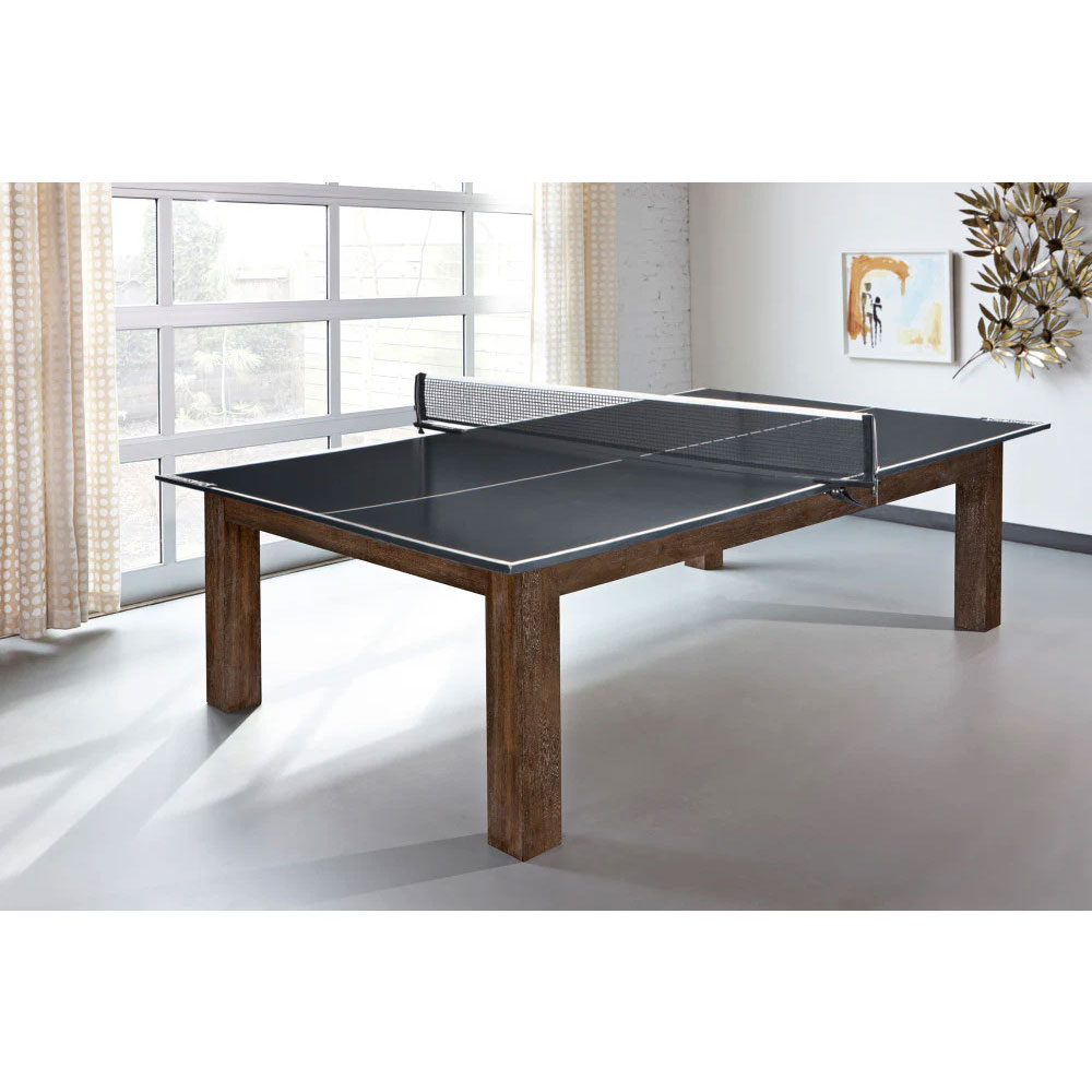 Table Soho moderne d'Brunswick, finition noyer, servant de table de ping-pong avec filet dans une pièce lumineuse. Surface de jeu foncée sur quatre pieds en bois robustes cubiques. Grandes fenêtres avec rideaux et déco.