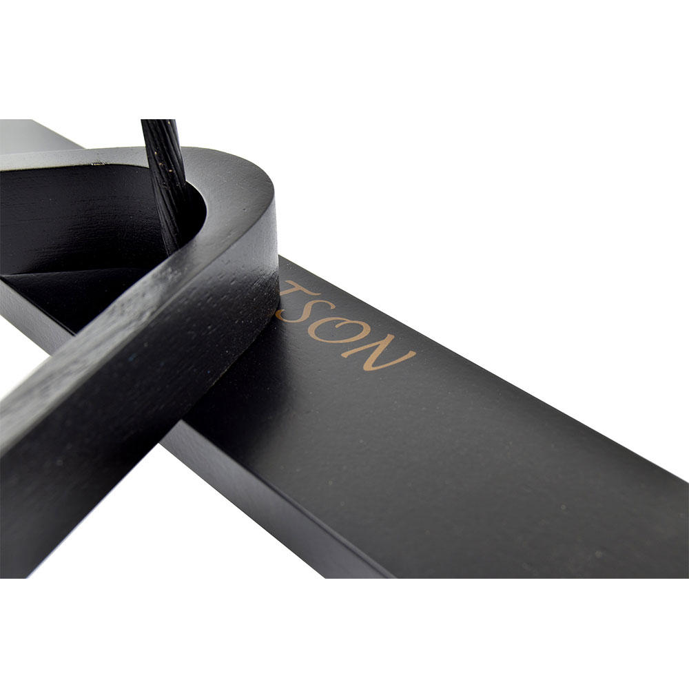Gros plan sur un objet noir mat présentant une ouverture incurvée à gauche, à travers laquelle passe un câble tressé de couleur sombre. Sur la surface plane à droite, on peut lire « SON » en lettres dorées. Fond blanc immaculé.