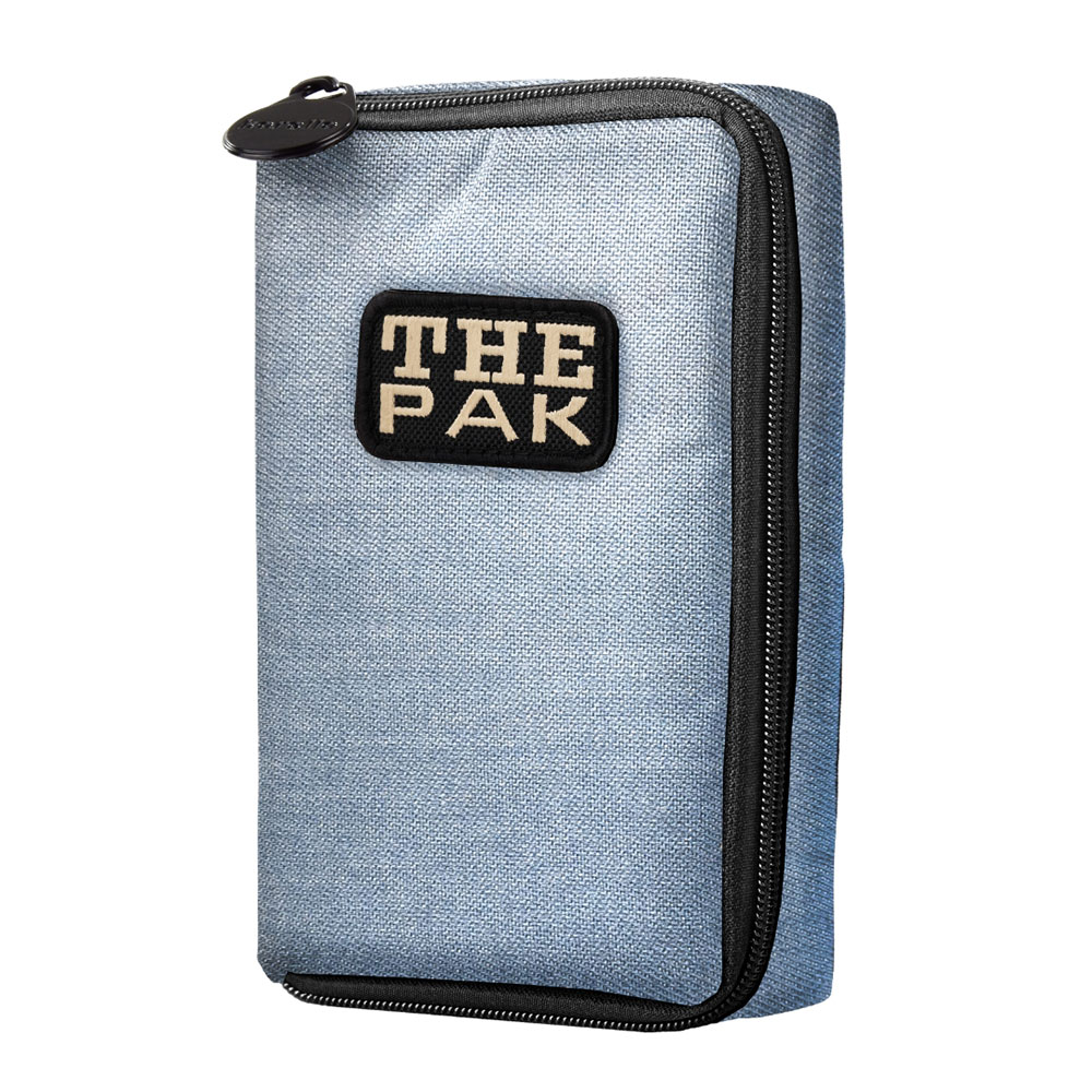 An upright, rectangular darts bag in light denim blue with a fine fabric texture. On the front, a black rectangular patch with white lettering reading ‘THE PAK’. Black zip at the top and on the right, with a small zip pull.