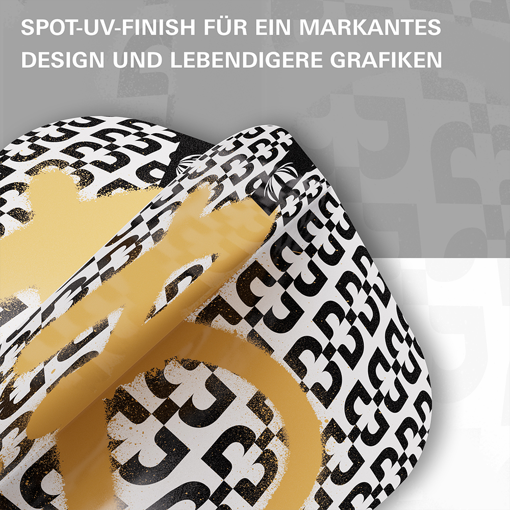 Close-up of a printed material: repeated black triplets on a white background form a chequerboard pattern. A golden, slightly speckled layer partly covers the pattern and is partly peeled away – indicating spot UV.